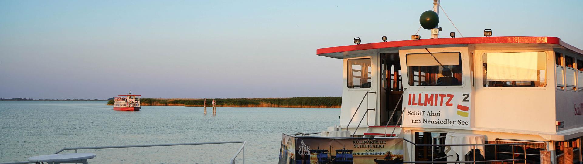 Steg, an dem ein Schiff parkt, rundherum der Neusiedler See.