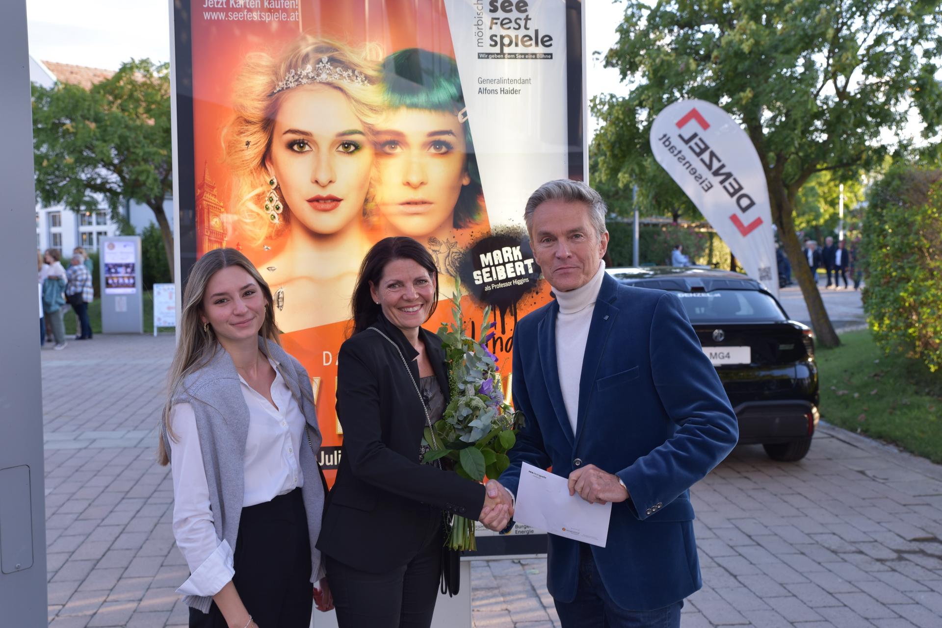 Generalintendant Alfons Haider mit zwei Besucherinnen der Seefestspiele Mörbisch vor dem Eingang zum Festspielgelände.